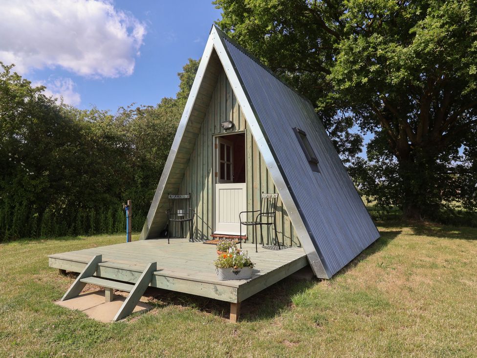 A cabin with a deck and chairs at 1 Bed Sleeps 2, Shared Bathroom in Monewden near Otley, Suffolk