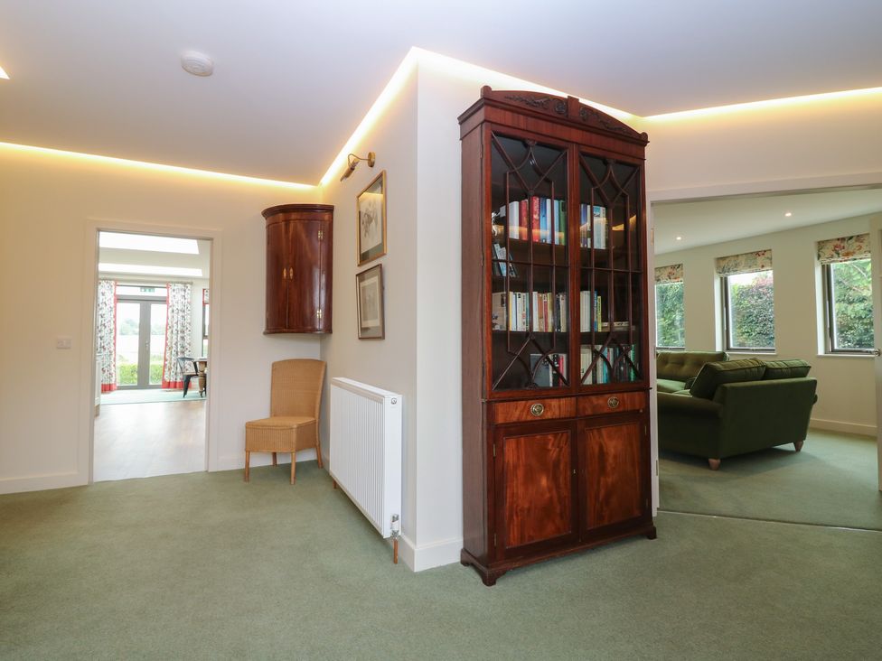 A hallway with a bookcase and chair at Lower Lodge in Cupar