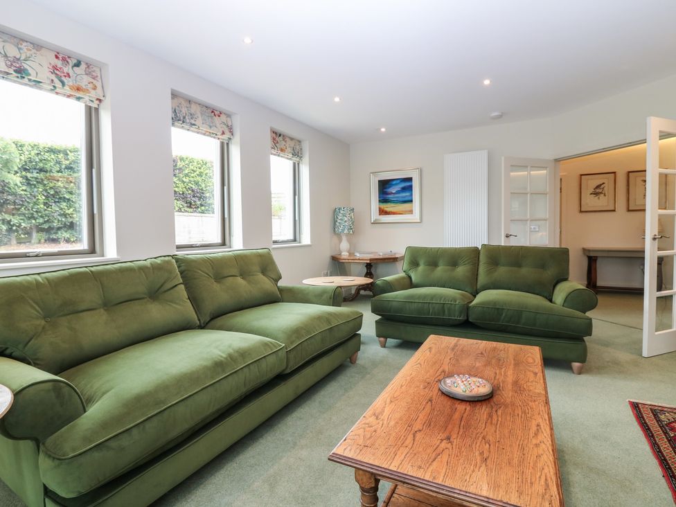 A living room with green sofas and a coffee table at Lower Lodge in Cupar