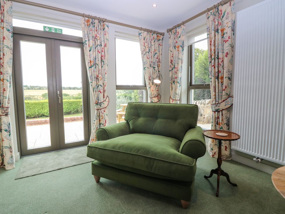 A living room with a green sofa and a round table at Lower Lodge in Cupar