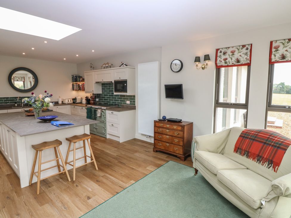 A kitchen with bar stools and a sofa at Lower Lodge in Cupar