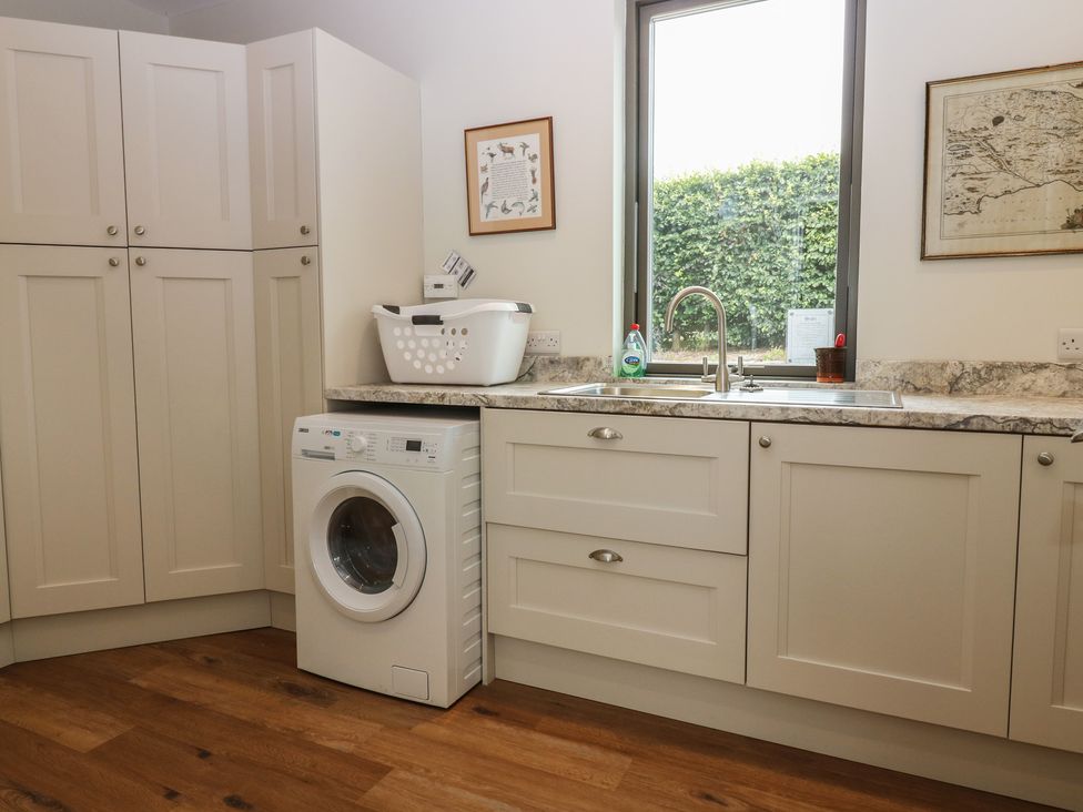 A laundry room with a washing machine and cabinets at Lower Lodge in Cupar