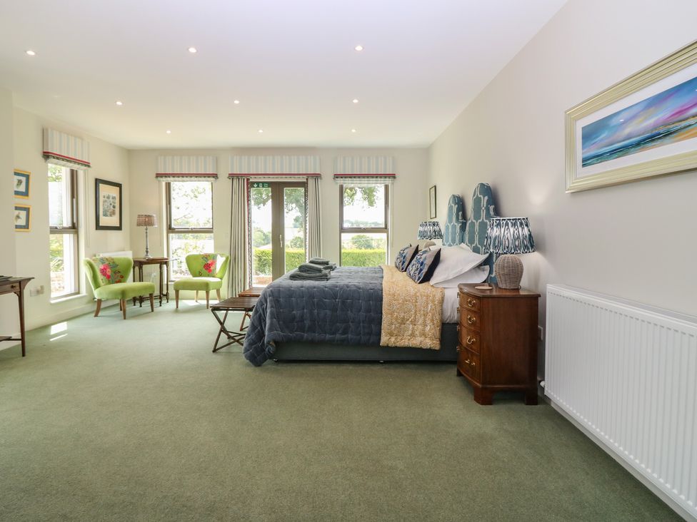 A bedroom with a bed and armchairs at Lower Lodge in Cupar