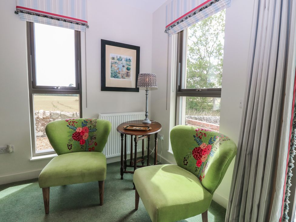 A sitting room with green chairs and a table at Lower Lodge in Cupar