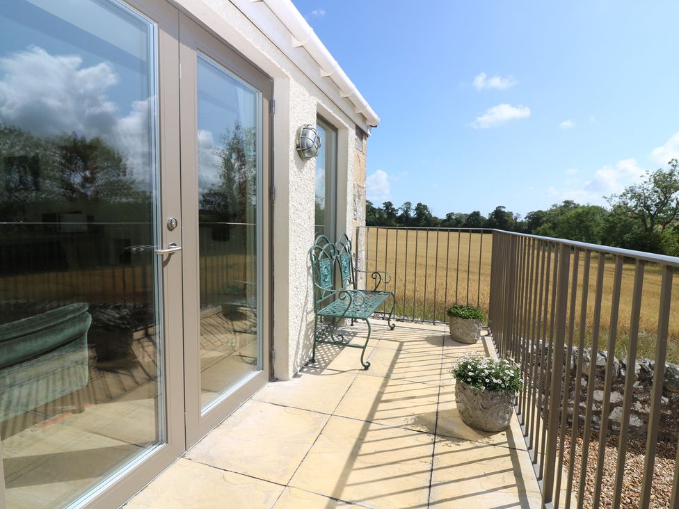A balcony with a chair and planters at The Barn, Lower Lodge Cupar