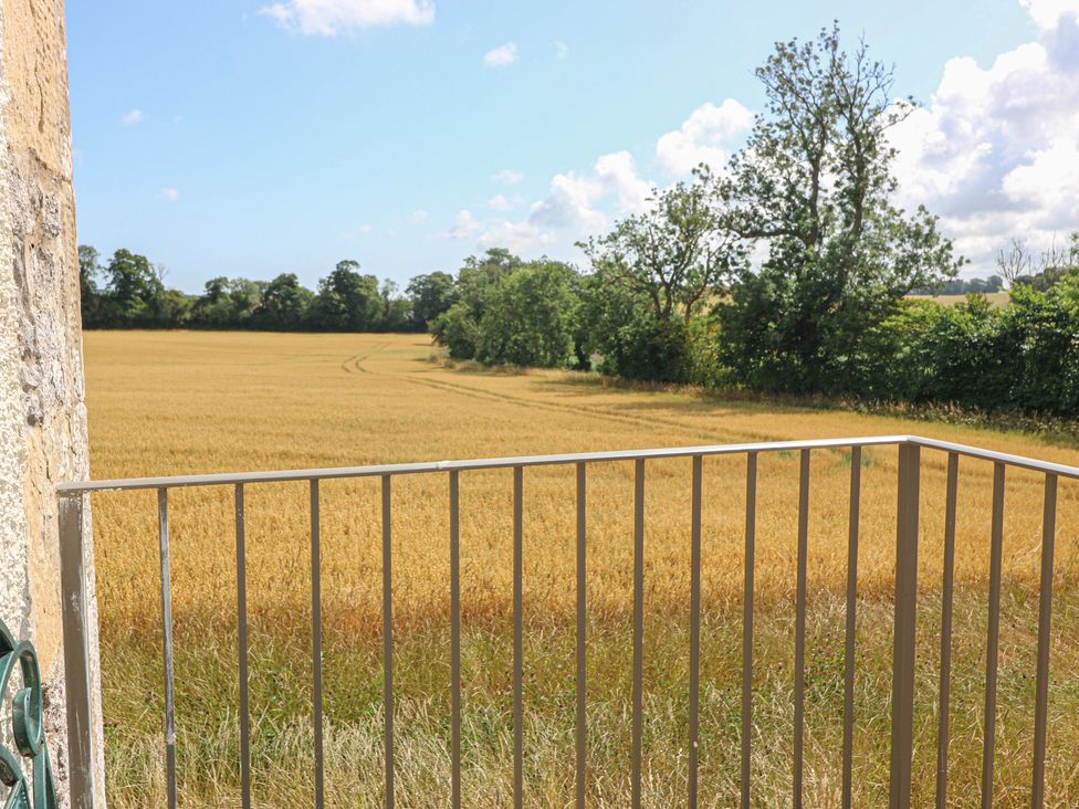 A view of a field with trees and a railing at The Barn, Lower Lodge in Cupar