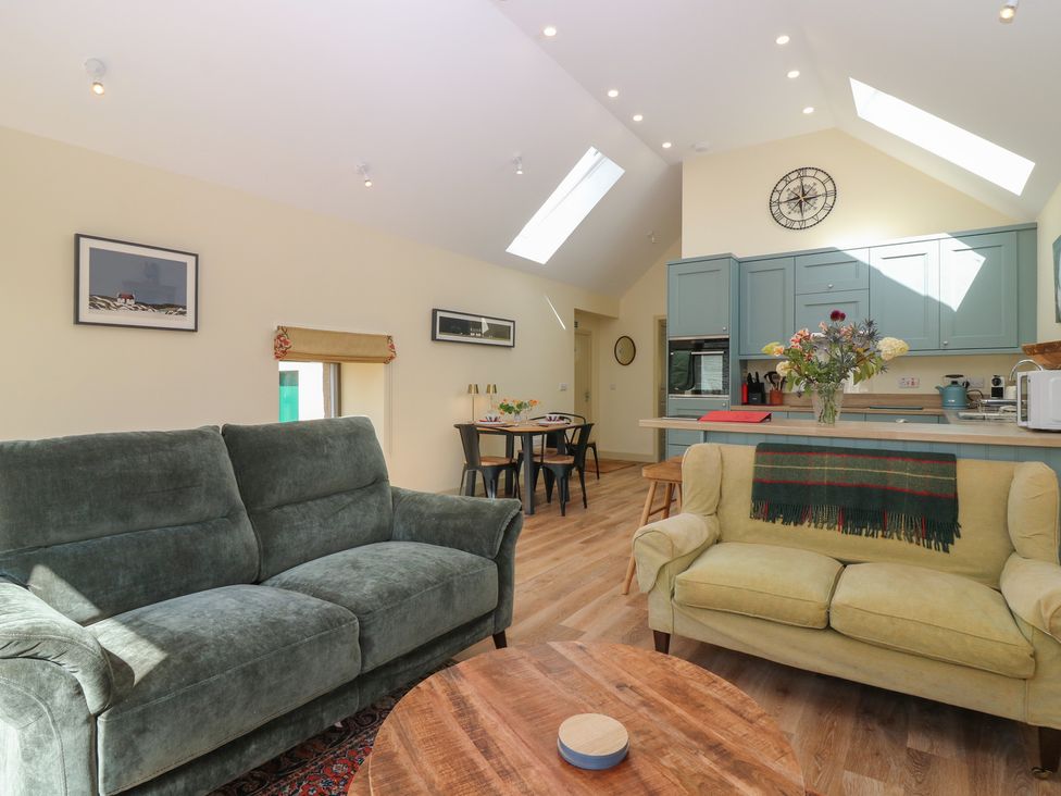 A living room with seating and kitchen area at The Barn, Lower Lodge, Cupar