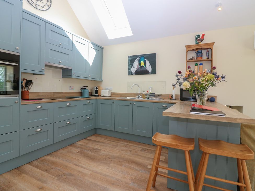 A kitchen with blue cabinets and bar stools at The Barn, Lower Lodge Cupar