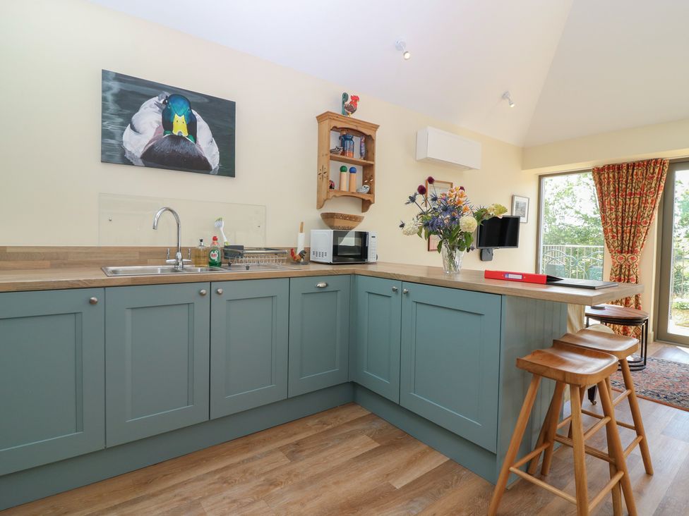 A kitchen with a sink, cabinets, and bar stools at The Barn, Lower Lodge in Cupar