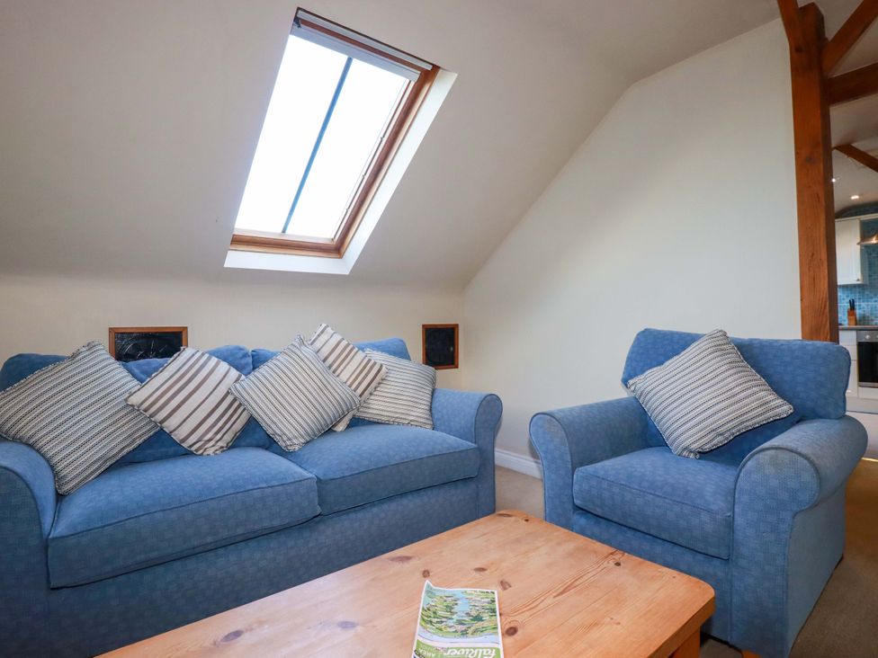 A living room with blue sofa and armchair at The Stables in Falmouth