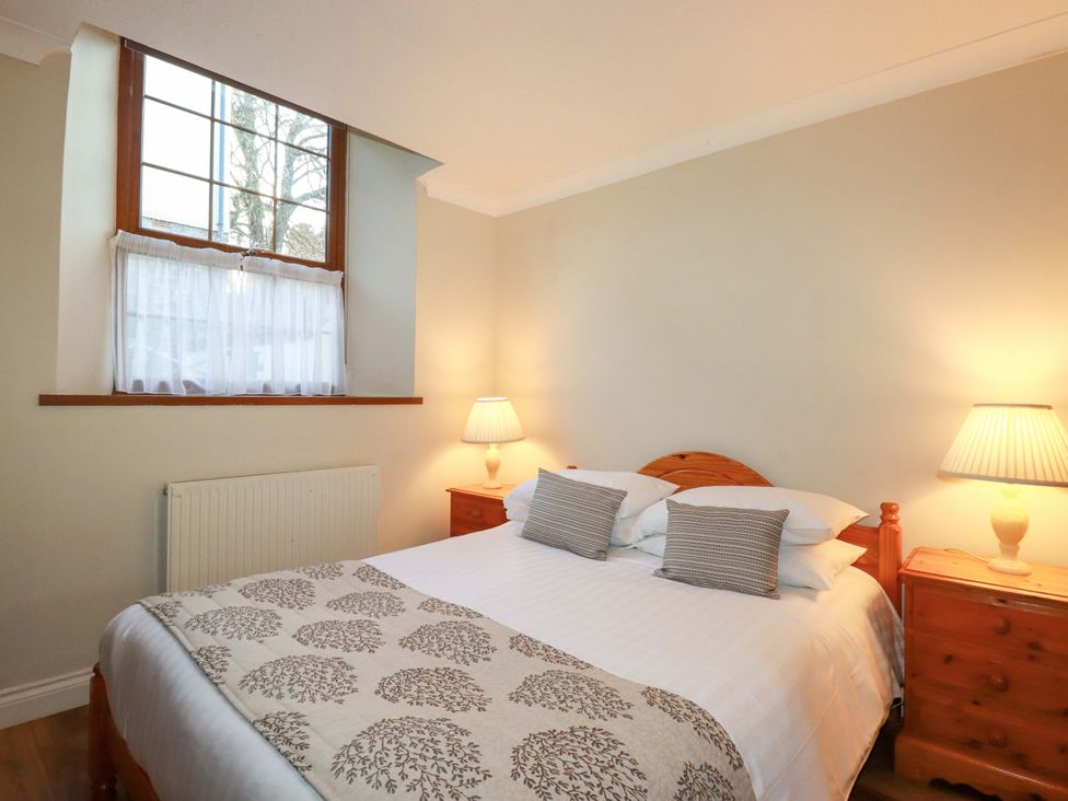 A bedroom with a bed and lamps at The Stables in Falmouth