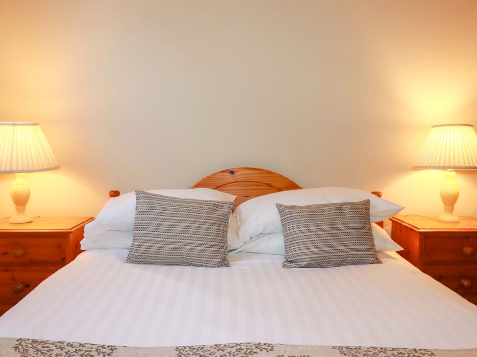A bedroom with a bed and lamps on nightstands at The Stables in Falmouth