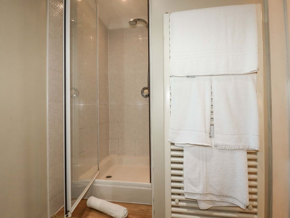 A bathroom with a shower and towels at The Stables in Falmouth