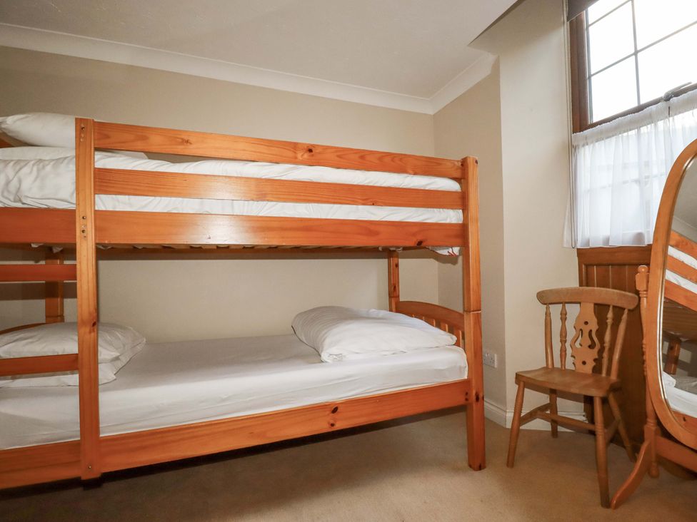 A bedroom with a bunk bed and chair at The Stables in Falmouth