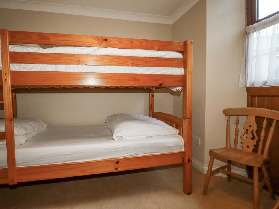 A bunk bed with pillows and a chair at The Stables in Falmouth