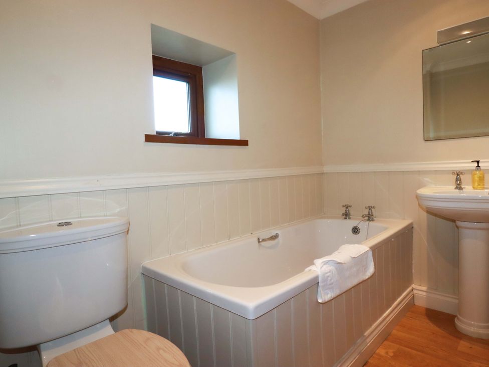 A bathroom with a bathtub, sink, and toilet at The Stables in Falmouth
