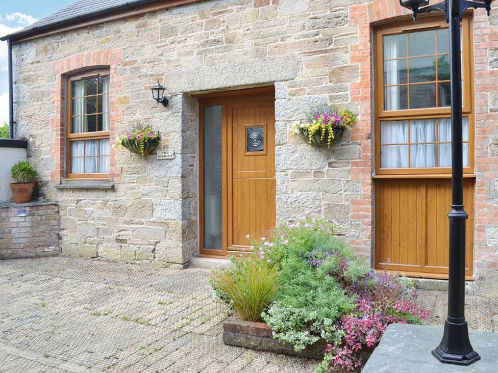 An outdoor entrance with a wooden door and flower pots at The Stables Budock Water near Falmouth