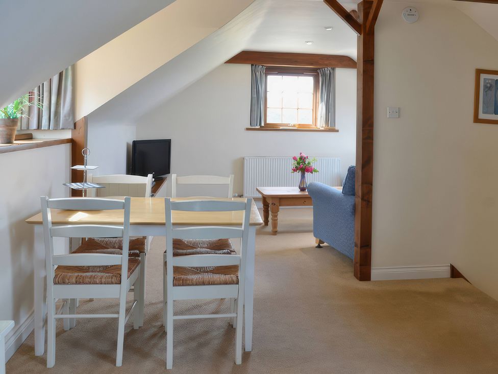 A living room with a table, chairs, sofa and television at The Stables in Budock Water near Falmouth