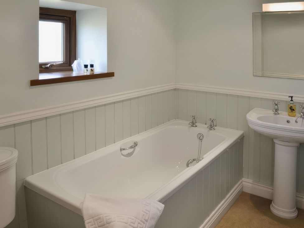 A bathroom with a bath tub, sink, and toilet at The Stables Budock Water near Falmouth