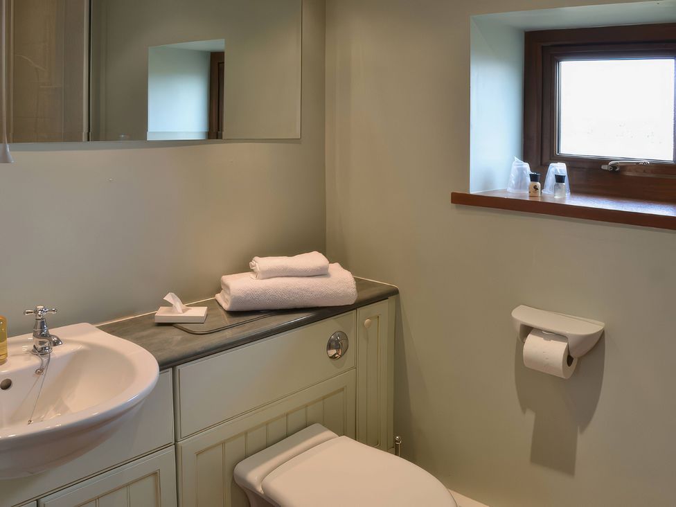 A bathroom with a sink, toilet, and towels at The Stables Budock Water near Falmouth