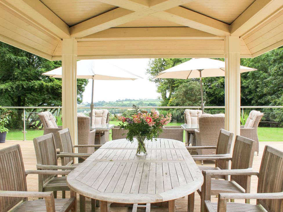 An outdoor patio with a wooden table and chairs at The Stables Budock Water near Falmouth