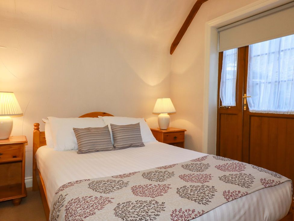 A bedroom with a bed and bedside tables at Farrier Cottage in Falmouth