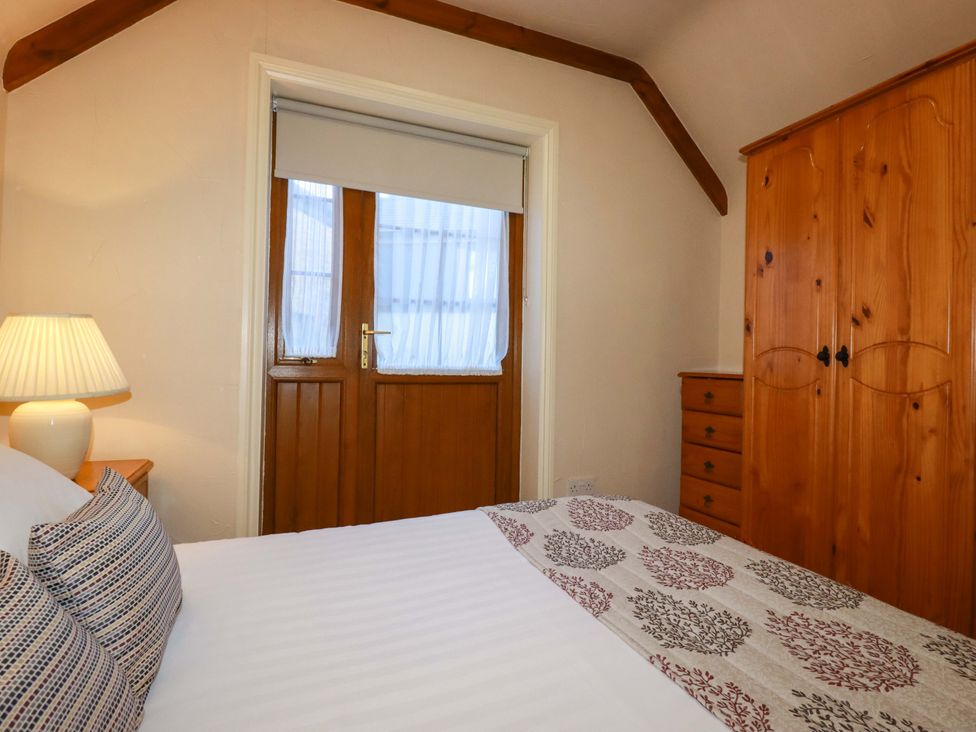 A bedroom with a bed and a wardrobe at Farrier Cottage in Falmouth