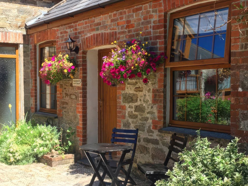 An outdoor area with flowers and seating at Farrier Cottage Budock Water near Falmouth