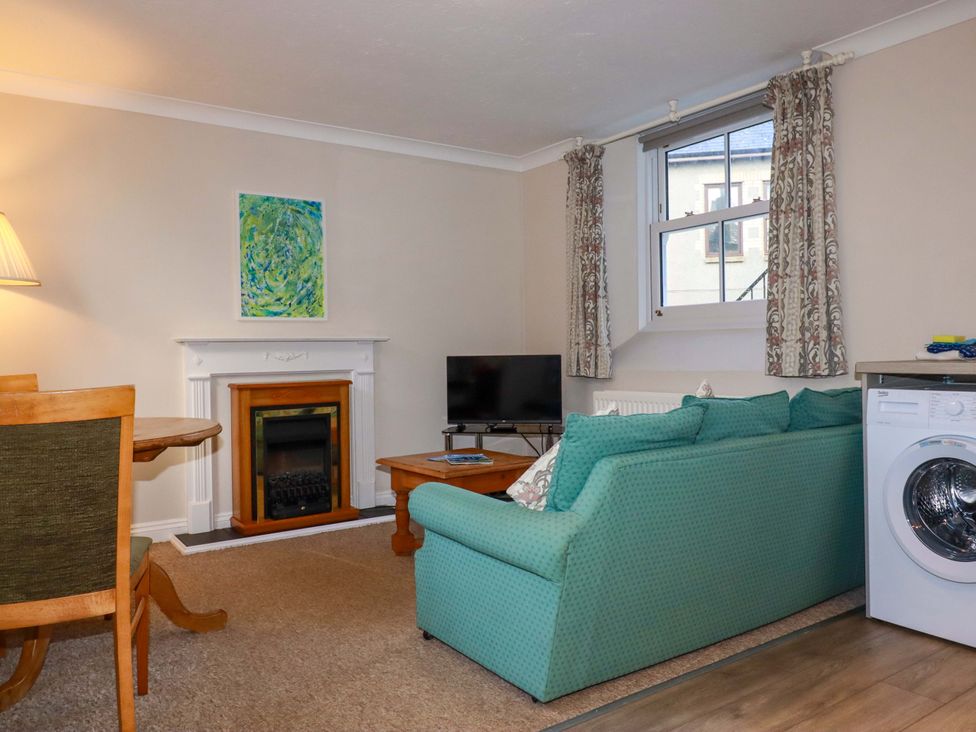 A living room with a sofa, television and fireplace at Horseshoe Cottage in Falmouth