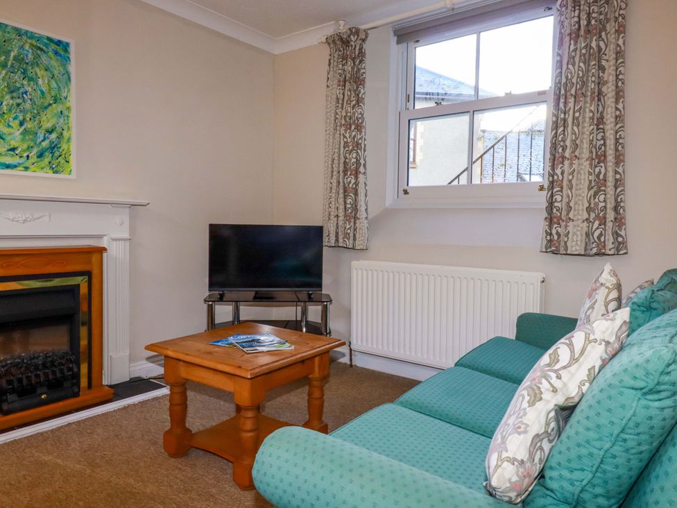 A living room with a sofa and television at Horseshoe Cottage in Falmouth