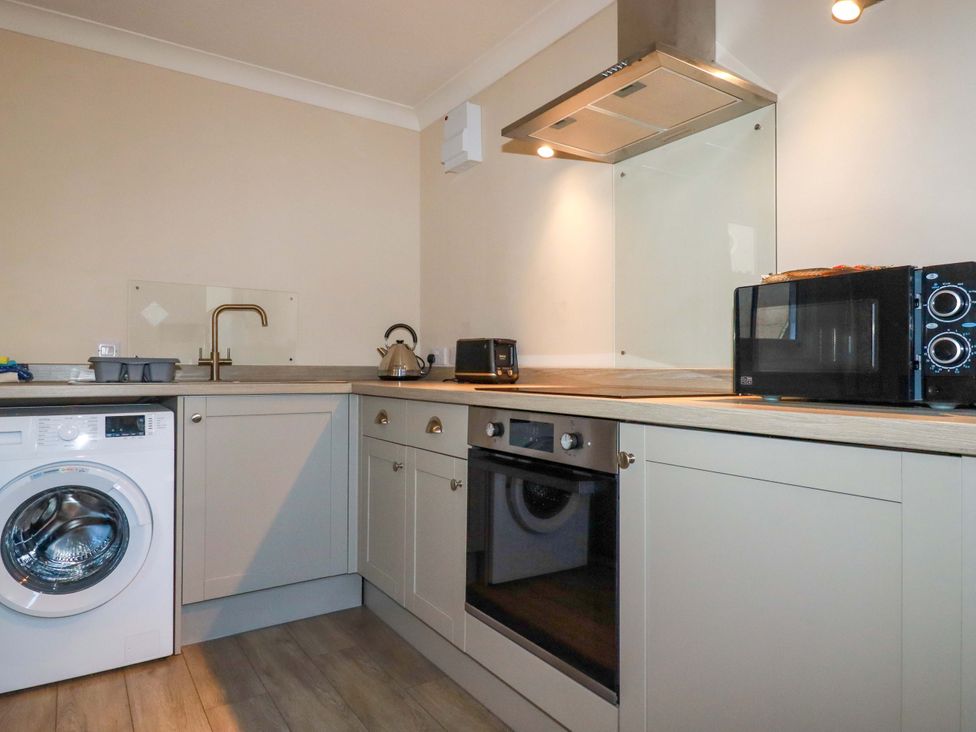 A kitchen with appliances including a washing machine and microwave at Horseshoe Cottage in Falmouth