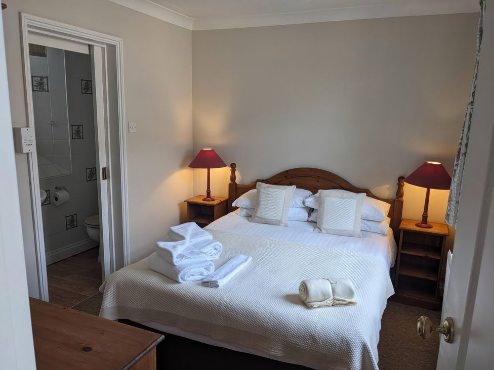 A bedroom with a bed and nightstands at Horseshoe Cottage Budock Water near Falmouth