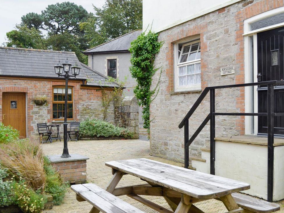 An outdoor area with a wooden table and chairs at Horseshoe Cottage Budock Water near Falmouth