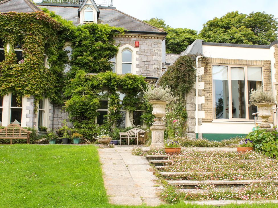 An outdoor garden area with a building and pathway at Horseshoe Cottage Budock Water near Falmouth