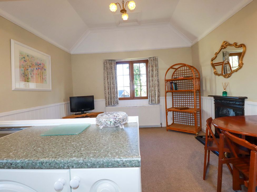 A living room with a television and bookshelf at The Hayloft in Falmouth