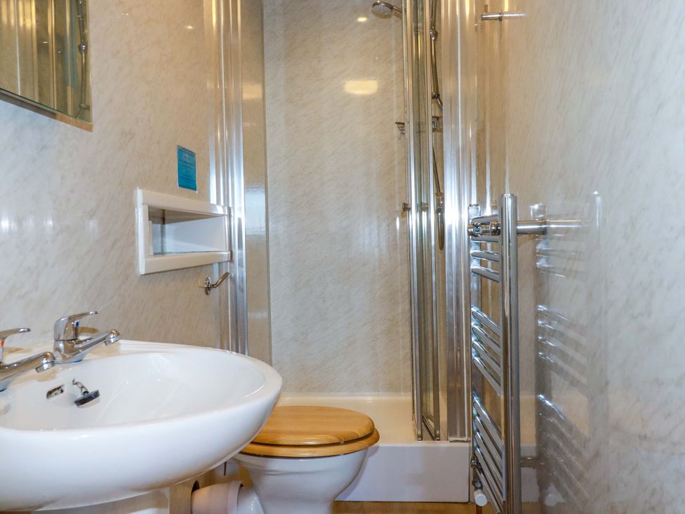 A bathroom with a sink, toilet, shower and towel rail at The Hayloft in Falmouth