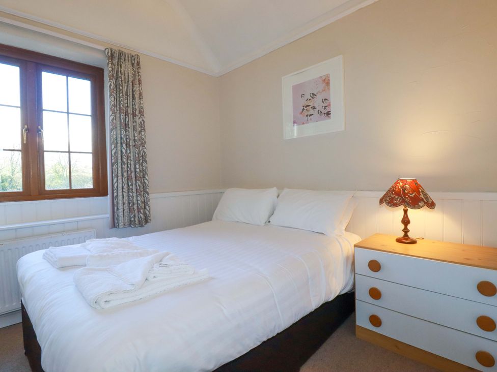 A bedroom with a bed and lamp at The Hayloft in Falmouth