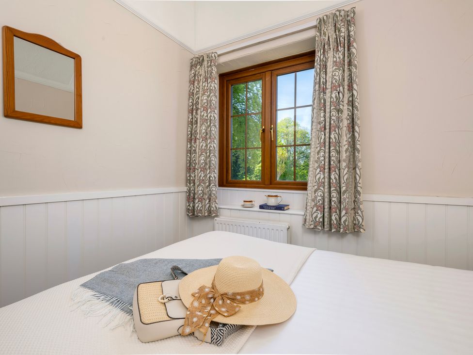 A bedroom with a window, mirror, and bed at The Hayloft in Budock Water near Falmouth