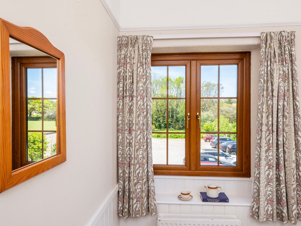 A room with a window and mirror at The Hayloft Budock Water near Falmouth
