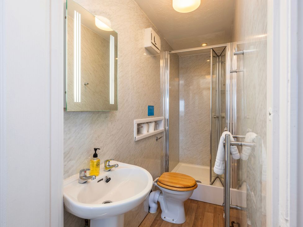 A bathroom with a sink, toilet, shower, and mirror at The Hayloft in Budock Water near Falmouth