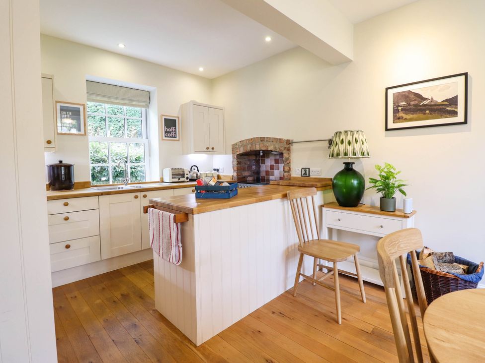 A kitchen with wooden cabinets and a window at Dolhiryd, Glyn Ceiriog, near Chirk