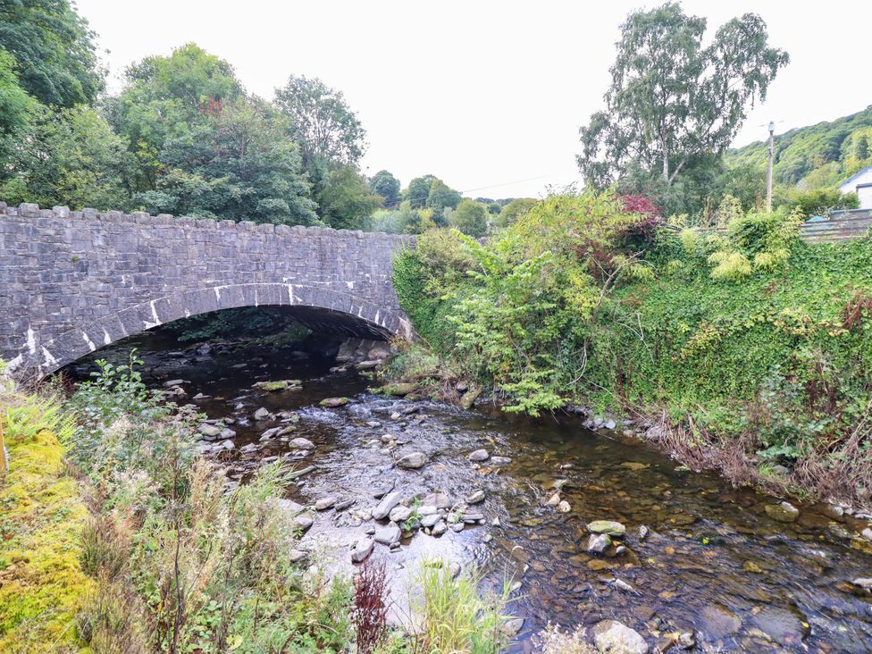 A bridge over a river surrounded by trees and vegetation at Dolhiryd, Glyn Ceiriog near Chirk