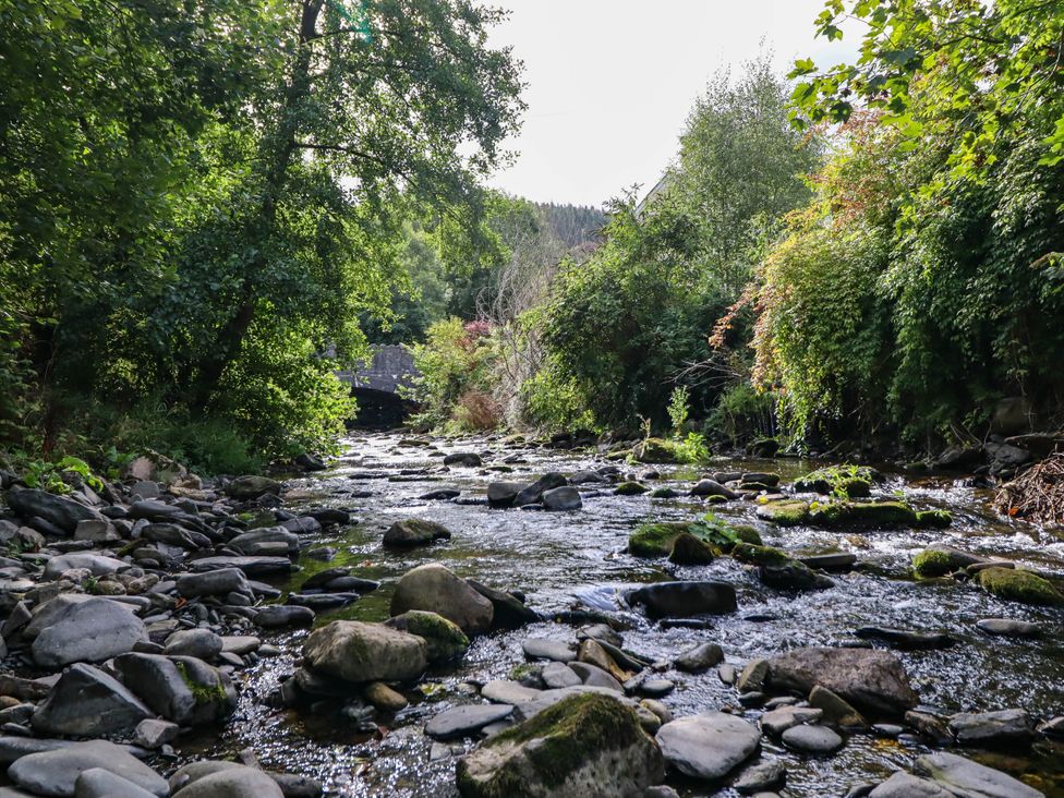 A river with rocks and trees near a bridge at Dolhiryd in Glyn Ceiriog, near Chirk