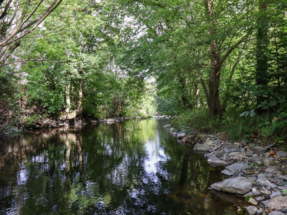 A river with trees and rocks along the shore at Dolhiryd in Glyn Ceiriog, near Chirk