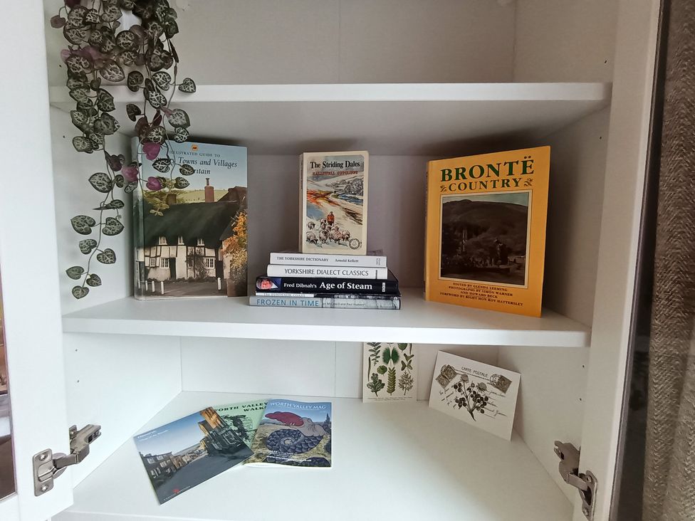 A shelf with books, postcards, and a plant at 14 Lindon Street