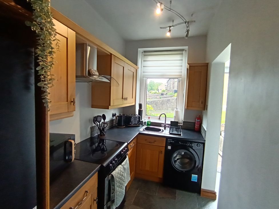 A kitchen with cabinets, sink, stove, and washing machine at 14 Lindon Street