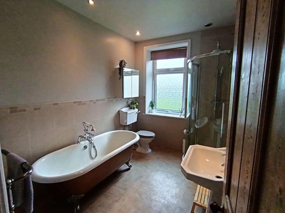 A bathroom with a bathtub, toilet, shower, and sink at 14 Lindon Street