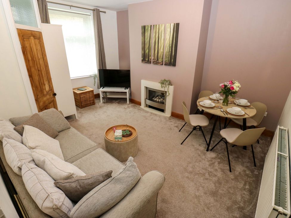 A sitting room with a sofa and dining table at Steam View Cottage Haworth