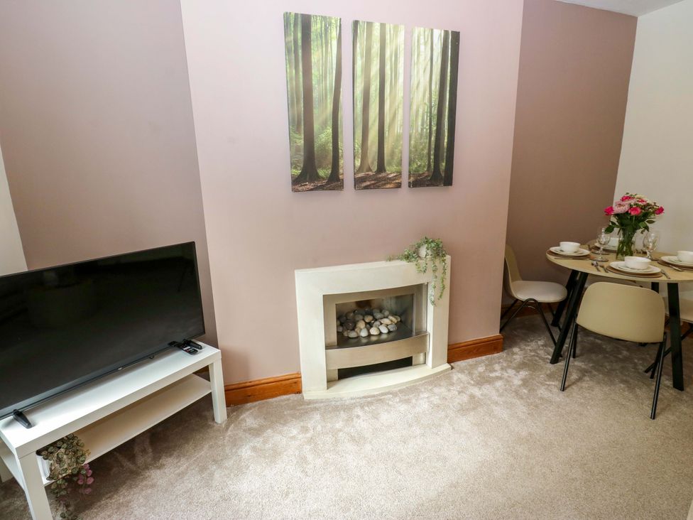 A living room with a television and dining table at Steam View Cottage in Haworth