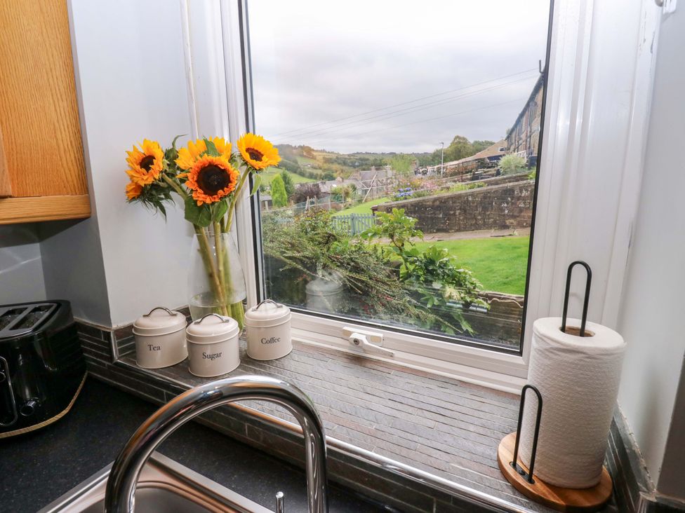 A kitchen with sunflowers in a vase by the window at Steam View Cottage in Haworth